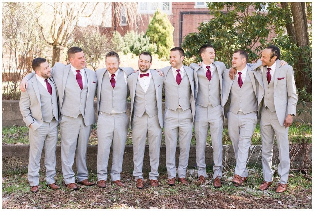 Groom with groomsmen with grey suits and red details at Aquinas College.
