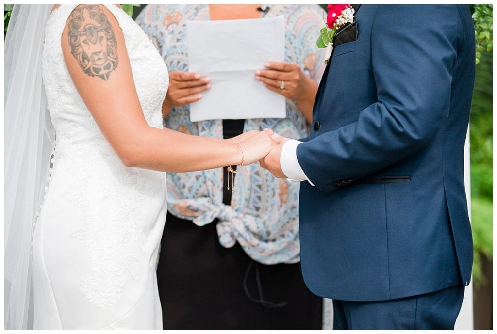 Bride and groom holding hands during wedding ceremony in Greenhouse Downtown Market wedding.