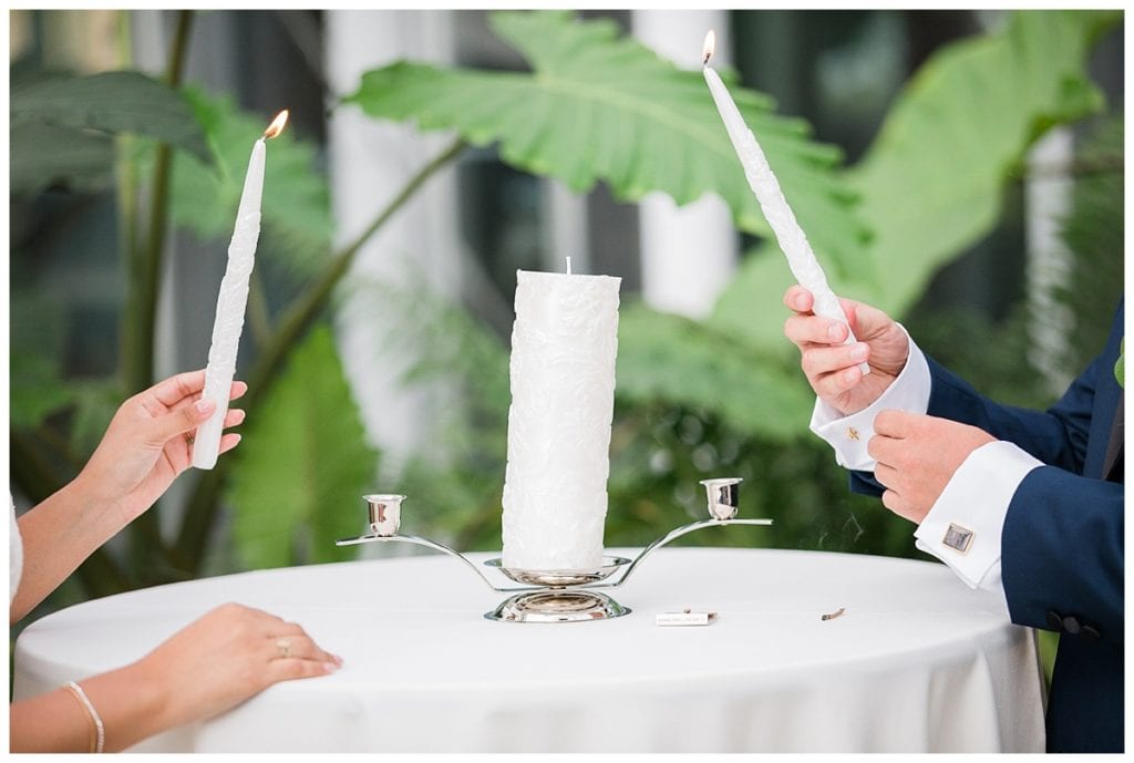 Bride and groom lighting unity candle in greenhouse wedding at Downtown Market.